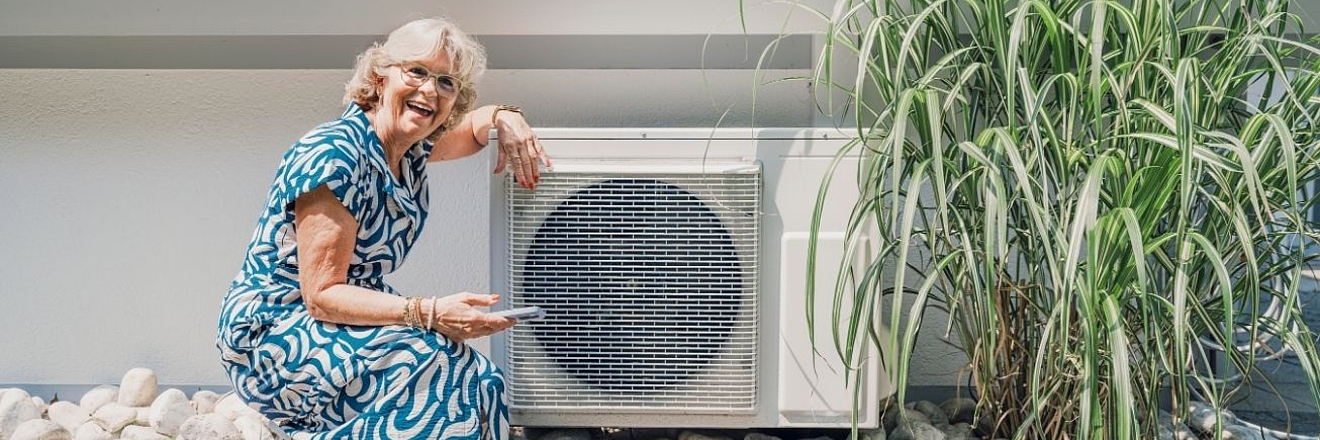 Smiling woman adjusting heat pump with smartphone in home garden