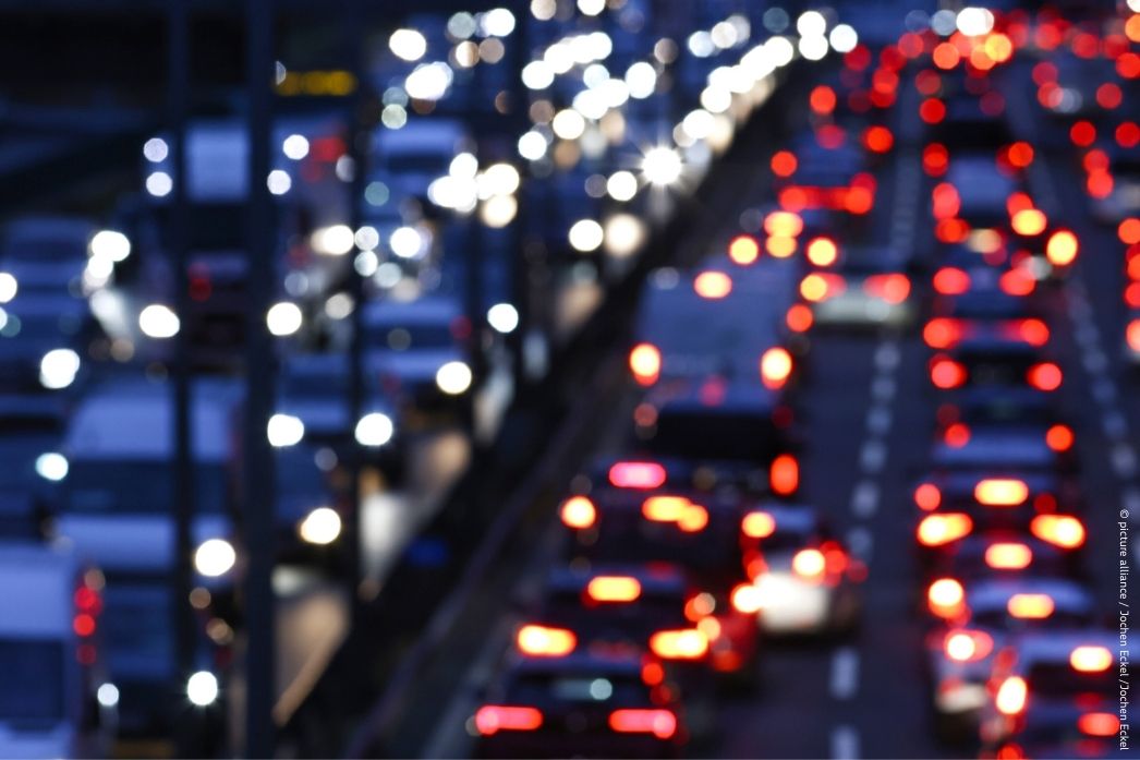  Blurred night-time view of heavy traffic on a multi-lane highway, with red tail lights and white headlights creating a bokeh effect.